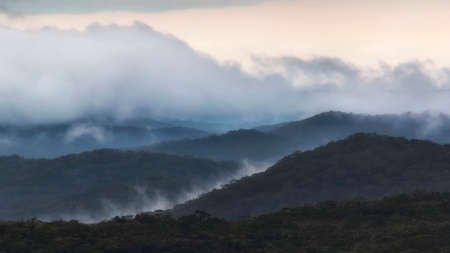 a group of clouds in front of a mountainの写真素材