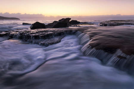 a waterfall going over a body of water at killcare beachの写真素材