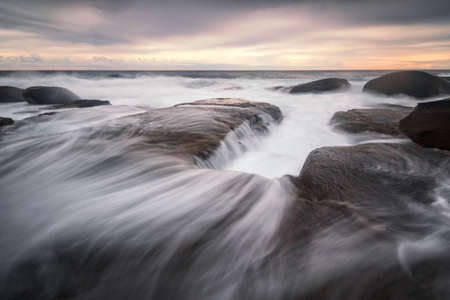 water flowing into the ocean on the coastlineの写真素材