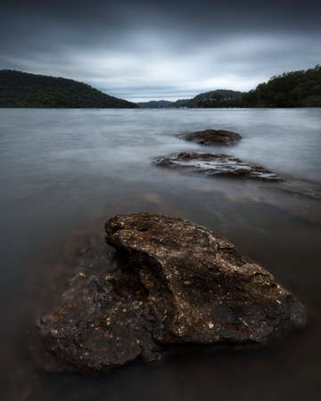 rocks in a large body of water surrounded by mountainsの写真素材