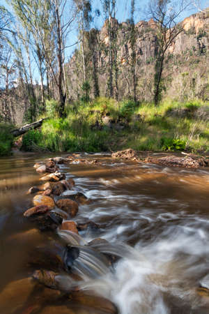 cascades in the creek at the foot of mountainsの写真素材