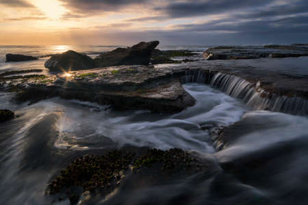 water flowing on the rocks at the beachの写真素材