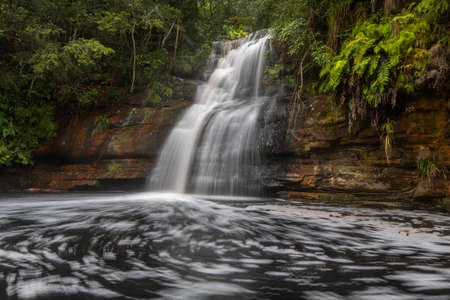 a waterfall with trees on the side of a riverの写真素材