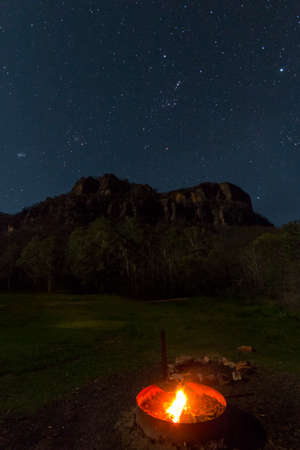 campfire at night with stars and mountainsの写真素材