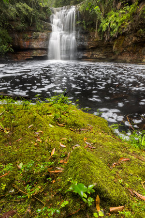 mossy ground in front of a large waterfallの写真素材