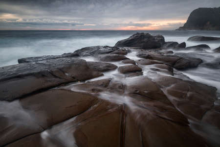 water on the rocks at the beach making shapesの写真素材