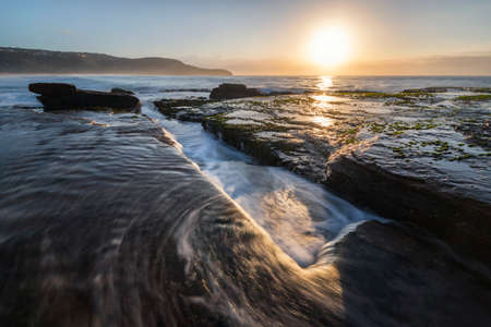 gutter in the rocks at sunrise on the beachの写真素材