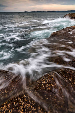 water flowing from the rocks into the ocean on the coastlineの写真素材