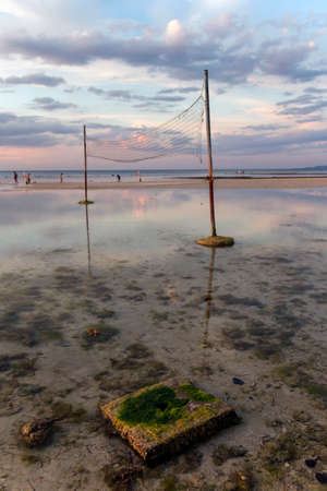 a close up of volleyball nets and clouds in the sky over a body of waterの写真素材