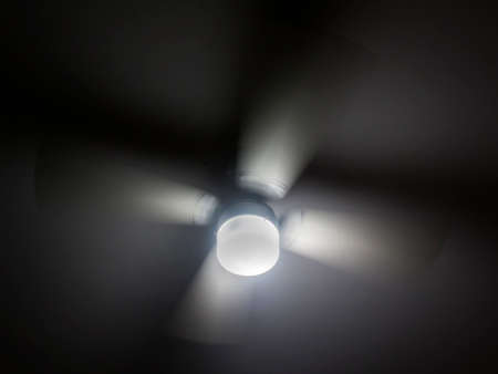 a close up of a fan and light on ceiling