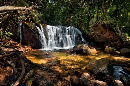 a large waterfall in a forest with sunlightの写真素材