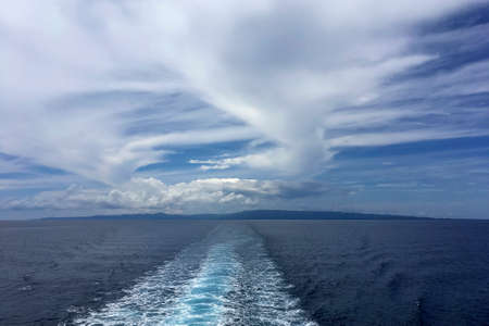 clouds in the sky over a body of water from back of boatの写真素材