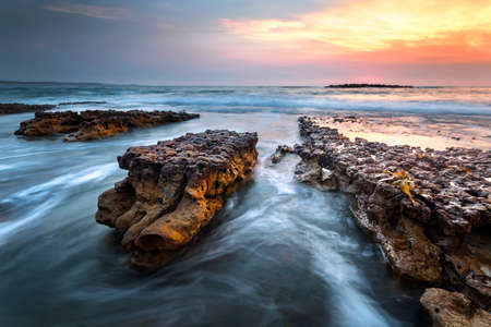 water and rocks at sunrise on the coastの写真素材