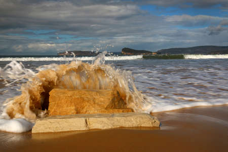 water splashing onto rocks at the beachの写真素材