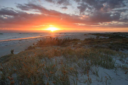 a sunset over a body of water on a beach in tasmaniaの写真素材