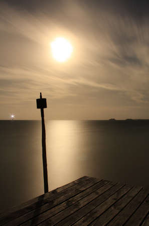 long exposure moon at night from pier in tongaの写真素材