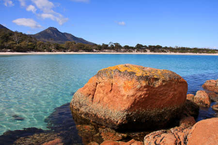 a rocky shore next to a body of water in tasmaniaの写真素材