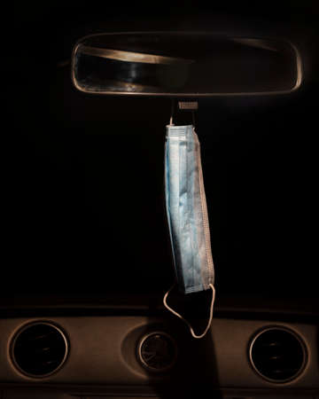face mask hanging from rear view mirror in a car at night