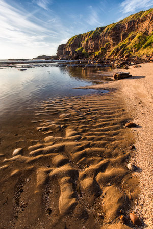 patterns in sand at the beach with clouds in skyの写真素材