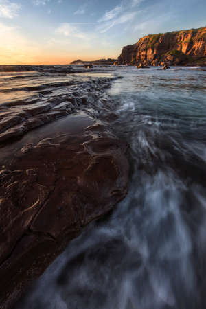 waves and rocks along coast at sunrise on windang island in nswの写真素材