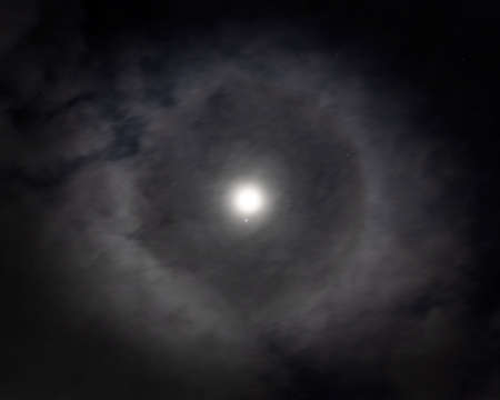 Lunar halo ring around the moon in night time sky with starsの写真素材