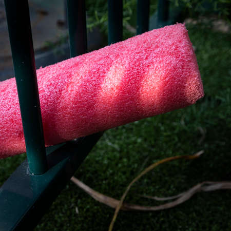 red pool noodle in pool fence and lightの写真素材