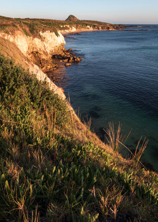 sunlight on cliff face overlooking water on Broughton Island in Australiaの写真素材