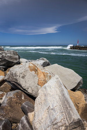Big rocks and ominous storm clouds in sky over water at breakwall on Wooli Wooli Riverの写真素材