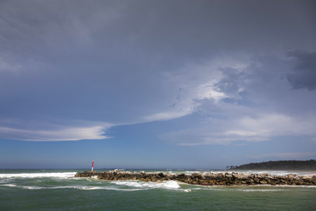Big rocks and ominous storm clouds in sky over water at breakwall on Wooli Wooli Riverの写真素材