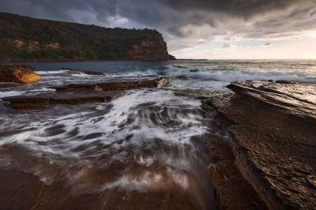 waves flowing over rocks at little beach on nsw central coast of australia during sunriseの写真素材