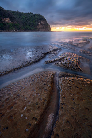 sunset over rocks and long exposure water at Little Beach on NSW Central Coast Australiaの写真素材