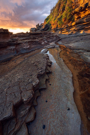 golden hour light on rocks during sunrise at little beach on nsw central coast of australiaの写真素材
