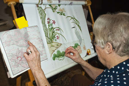 Lady busy at work on a complicated cross stitch.の写真素材