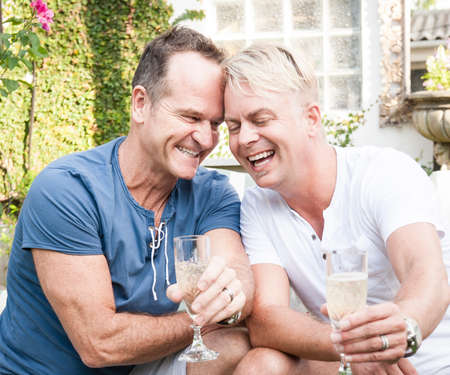 Two handsome gay men enjoying time together outdoors in their gardenの写真素材