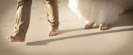 Close up view of couple's feet walking along beachの写真素材
