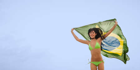 Young attractive woman in green bikini running with Brazil flagの写真素材