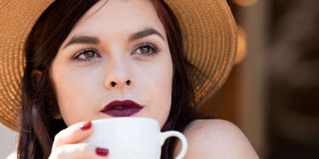 close up of young attractive woman sitting at cafe drinking coffeeの写真素材