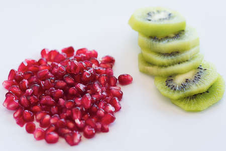 Pomegranate with Kiwi fruit and slices on white background with copy space.