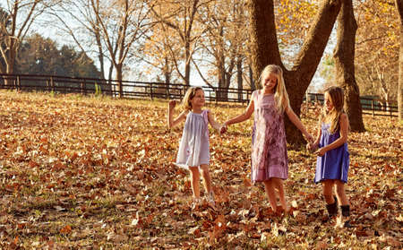 Young girls children kids playing running in fallen autumn leavesの写真素材