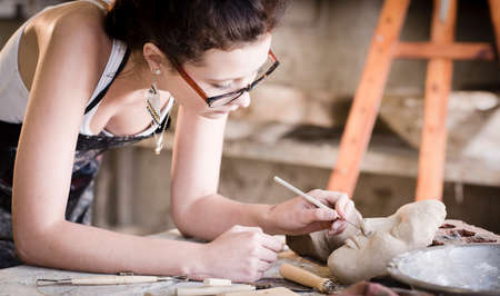 young artist moulding raw clay in art studio