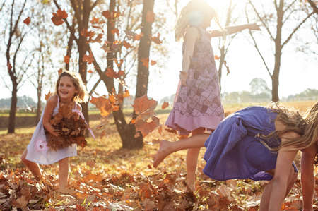 Young girls children kids playing running in fallen autumn leavesの写真素材