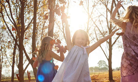 Young girls children kids playing running in fallen autumn leavesの写真素材