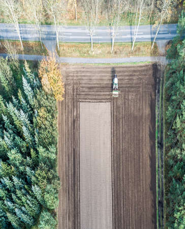 Vertically aligned aerial photograph taken with the drone of an area of arable land treated by a tractorの写真素材