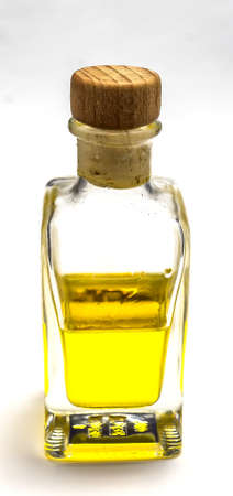 Semi-filled bottle with a yellow liquid and a cork stopper in front of a white backgroundの写真素材