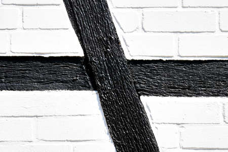 Detail of the side wall of a half-timbered house with black wooden beams and whitewashed walls of...