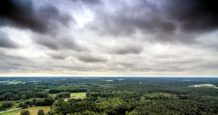 Aerial view of a dense wooded area in Germany, which is crossed by a road at the edge of a city, with dramatic sky , made with droneの写真素材