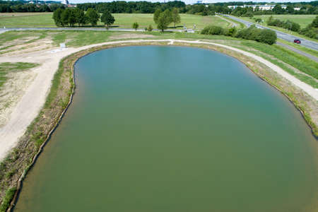 Rainwater retention basin with turquoise coloured water, taken diagonally from the air with a drone, Germanyの写真素材