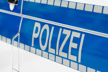 Inscription "Police" in white luminous colour on a blue background on the side of a police car, Germanyの写真素材