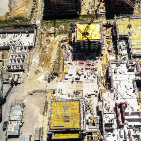 Vertical view from a great height of a square building shell covered with yellow sealing mats,...