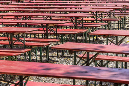 Ugly old red wooden benches and tables, from which the paint peels off, in a beer garden in Hannover